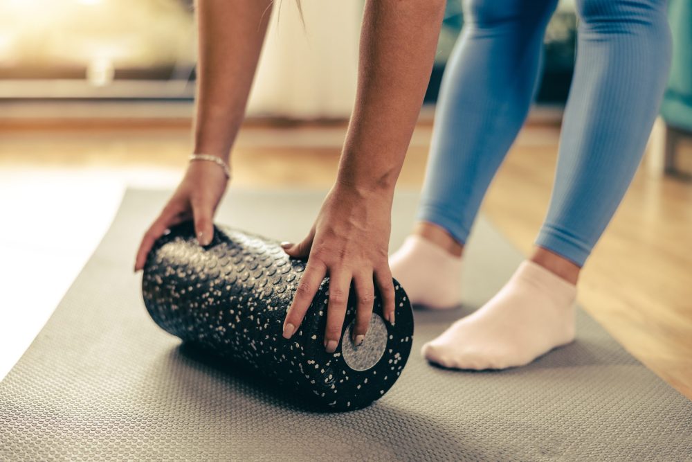Cropped shot of a young woman using a foam roller while doing training at home.
